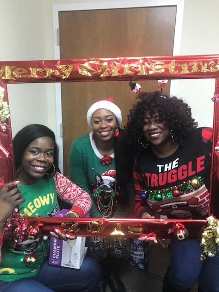 Beaufort staff memebers posing in their Christmas sweaters holding a red frame.