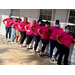 9 women posing next to building in pink shirts