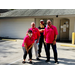 group of 4 people in parking lot posing, 3 wearing pink shirts